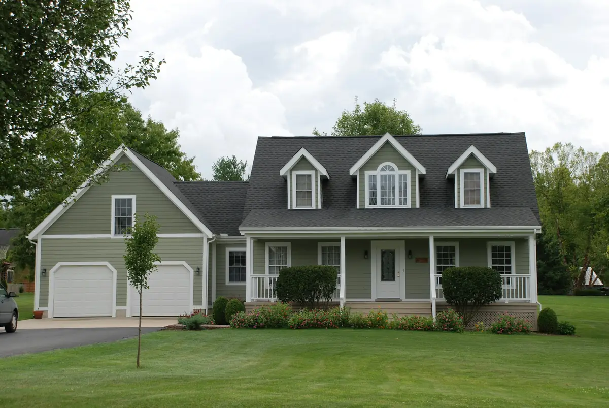 White and grey house behind a green lawn