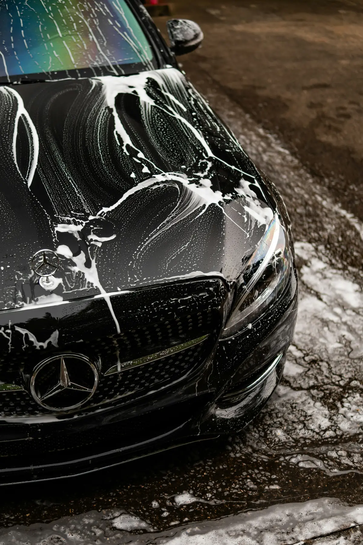 Black car covered in soap suds during a wash