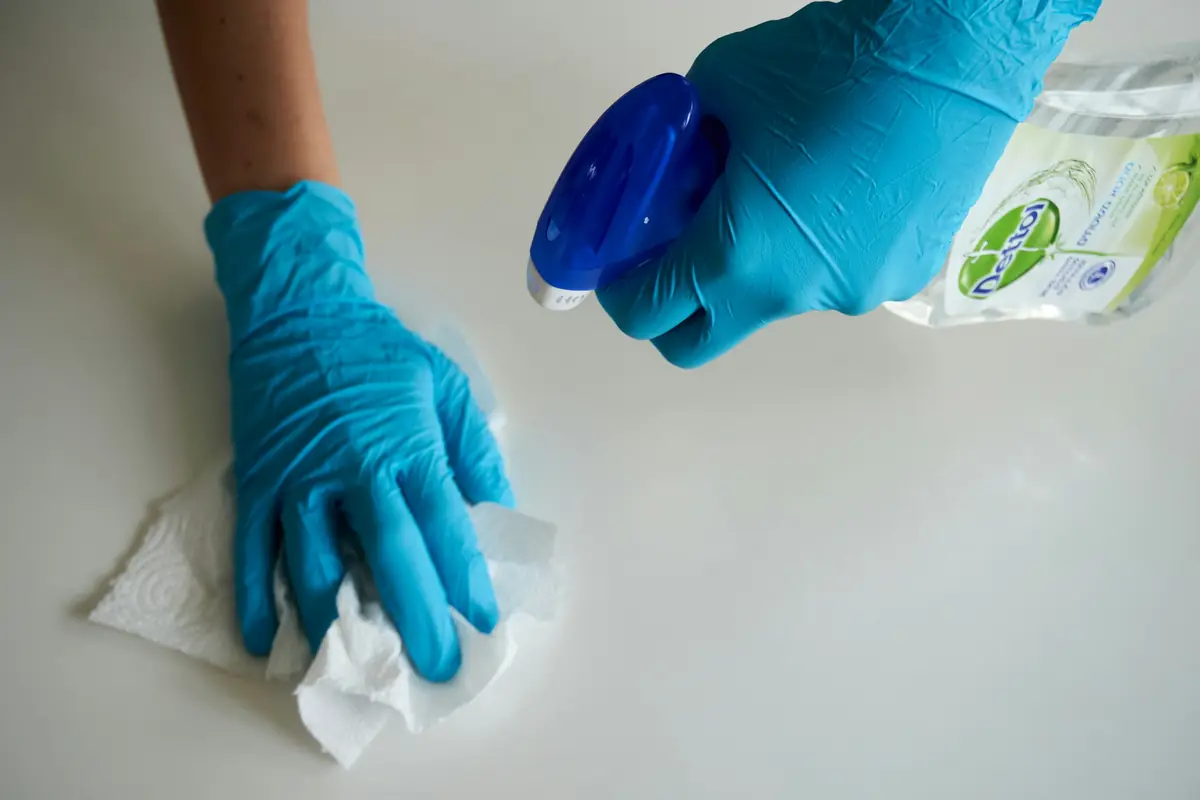Gloved hands wiping a surface